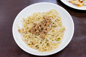 A bowl of Taiwanese-style dry noodles topped with savory minced pork sauce, scallions, and soy-based seasoning. A beloved comfort food offering rich umami and chewy texture.