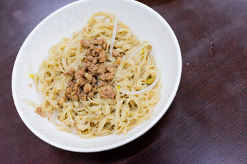 A bowl of Taiwanese-style dry noodles topped with savory minced pork sauce, scallions, and soy-based seasoning. A beloved comfort food offering rich umami and chewy texture.