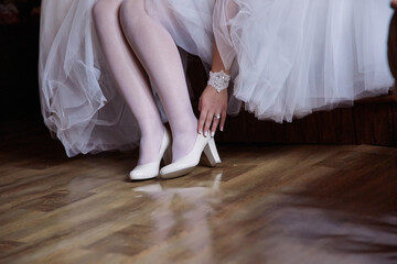 A woman in a wedding dress is bending over to put on her shoes