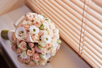A bouquet of flowers sits on a table next to a window