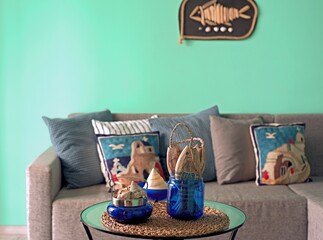 Marine style in the apartment interior - a sofa with pillows and a table with shells and fish figures.