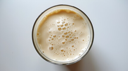 A glass of frothy coffee rests on a clean white surface, ready to drink.