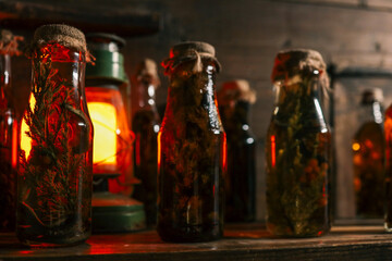Row of vintage glass bottles filled with herbal infusions and berries on wooden shelf, glowing...