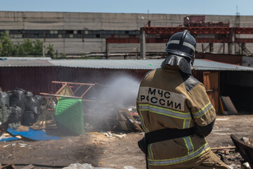 A professional firefighter puts out a garbage fire at a factory. Russian National Fire Service