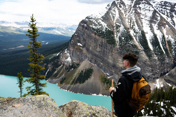 Hiker with yellow backpack looking at the turquoise lake