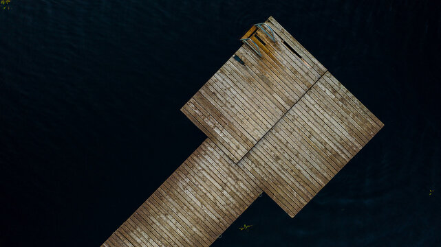 Aerial top-down view of wooden pier in the dark lake.