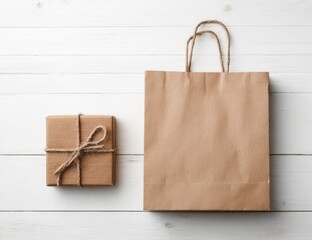 A small, twine-tied gift box rests beside a larger, empty kraft paper shopping bag on a white wood surface