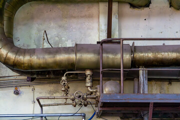 Old industrial pipes with valves and fittings mounted on a worn wall inside an abandoned factory....