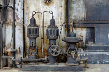 Old cast iron industrial pumps in a rusty, weathered boiler room. Visible signs of wear and patina...