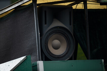 large black outdoor speaker in temporary stage setup with protective canopy and fabric side panels,...