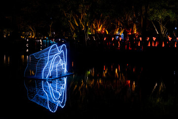 A serene alley illuminated by rows of glowing lanterns suspended above, casting warm light onto the narrow pathway below. The nighttime setting evokes a nostalgic, peaceful mood with traditional cultu
