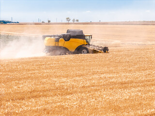 Obraz premium Combine harvester working through crop field with dust and debris