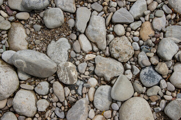 Smooth river stones of various shapes, sizes, and colors on a sunny day create a natural, calming...