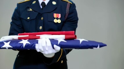 A soldier in full uniform carefully folds an American flag during a memorial service. The act symbolizes respect and honor for those who served. This moment showcases tradition and patriotism - Powered by Adobe