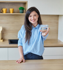 Portrait of a young woman gettyng ready for work drinking a glass of water for hydration standing...