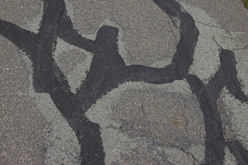 Cracks on asphalt repaired with bitumen mastic and fine gravel in a seamless European-style patch,...