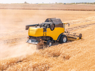 Top view of farming equipment working in golden grain field from above