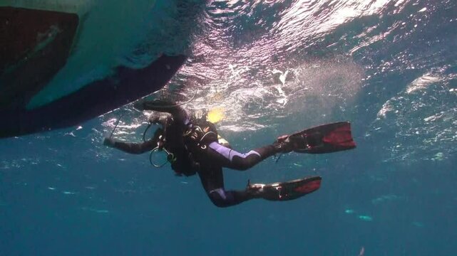 Scuba diver descends into the deep blue sea off the coast of La Palma, Canary Islands. Sunlight filters through the surface as the diver explores the ocean depths beneath a boat.