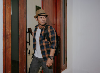 Asian man with backpack entering and opens the doors hostel or apartment. Young male tourist check...