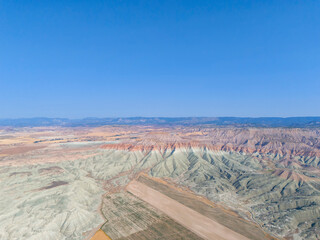 Nallıhan High-angle view of a colorful, sculpted landscape with a paved runway. An aerial shot showcasing a breathtaking, colorful landscape with various shades of pale orange, pink, and muted greens.