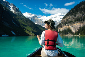 Person paddling canoe on turquoise lake