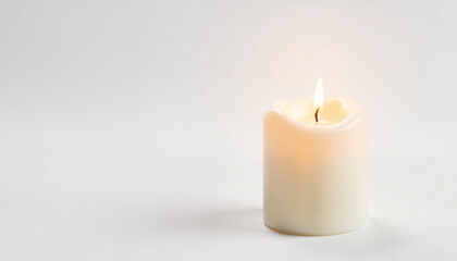 White candle glowing gently on light background  
