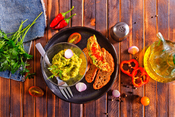 Traditional Mexican Dip Sauce Guacamole in a bowl with bread toasts