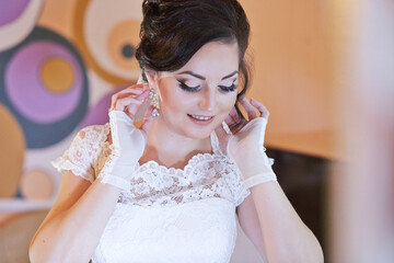 A woman is getting ready for a wedding and is putting on her gloves