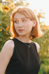 Young woman in black dress with silver necklace in sunflower field