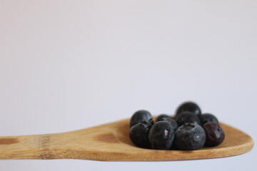 Arándanos en cuchara de madera (fondo blanco)
