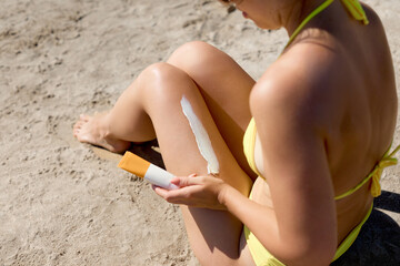 Closeup on female Hand applying sunscreen cream on Leg. Skincare. Sun protection sun cream, on her...