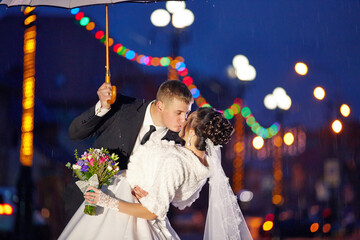 A bride and groom are kissing under an umbrella