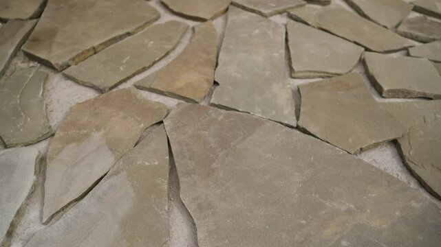 Construction workers are installing a flagstone patio, carefully arranging irregular-shaped stones
