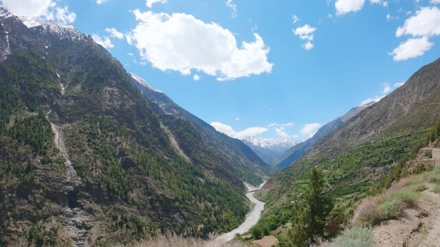 4K shot of river Chenab flowing between the two Himalayan mountain peaks with clouds above it as seen on the way towards Udaipur in Pattan valley, Lahaul, Himachal Pradesh, India. Scenic background.