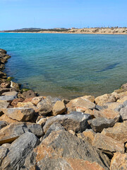 Coastal landscape with rocky shore, sand dunes, and clear blue sky