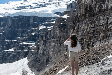 Woman wearing a hat looks at massive snow-covered cliffs