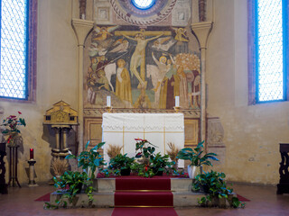 Floral decorations surrounding altar, highlighting fresco of crucifixion during Corpus Domini...
