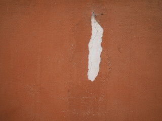 Close up of a terracotta wall in Cremona, Lombardy, revealing peeling plaster and textures of decay...