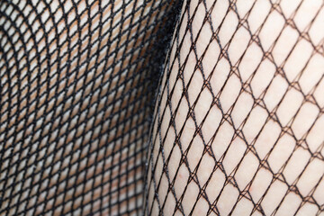 Close up of black fishnet tights on skin legs curves abstract background