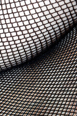 Close up of black fishnet tights on skin legs curves abstract background