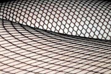 Close up of black fishnet tights on skin legs curves abstract background