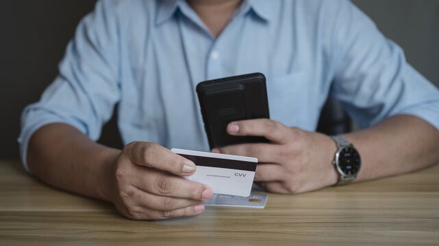 Businessman using smartphone and credit card for online payment. Secure financial transaction and digital banking concept.