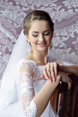 A woman in a white wedding dress is sitting on a chair with her hands on her lap