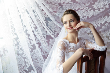 A woman in a white wedding dress sits on a wooden chair