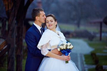 The bride is wearing a white dress and the groom is wearing a blue suit