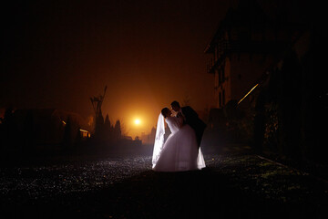 A bride and groom are kissing in the rain