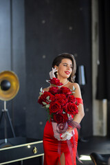 gorgeous girl in red dress with bouquet of red roses