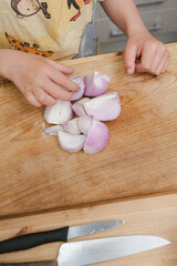 Child preparing chopped onions on a kitchen cutting board
