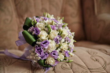 A bouquet of flowers with white and purple flowers is sitting on a couch