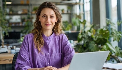 Confident businesswoman smiles serenely while working on her laptop in a modern, plant-filled office.